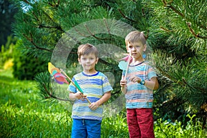Two happy children playing in garden with windmill pinwheel. Ado