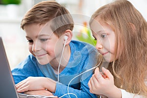 Two happy children playing with laptop and listening music with