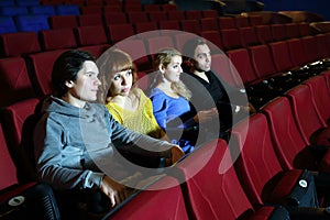 Two happy couples look movie and talk in cinema theater