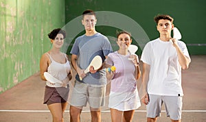 Two happy couples after playing paleta fronton on tennis court