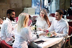 Two happy couples sitting at outdoor restaurant