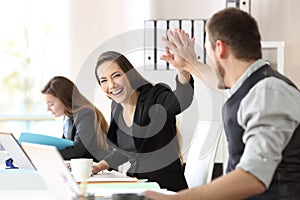Two happy coworkers celebrating success at office photo