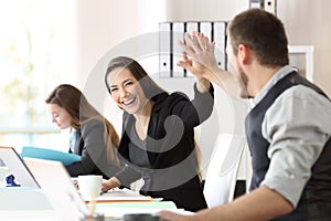 Two happy coworkers celebrating success at office