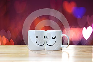 Two happy cups on wood table with heart bokeh background