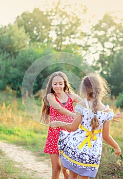 Two Happy cute  little girls having fun and dancing at sunny summer day outdoors