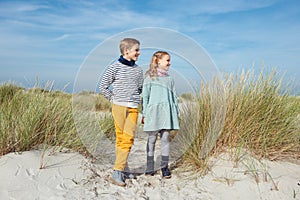 Two happy cute teenager brother and siater staing on beach with white sand on Baltic sea