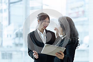 Two happy diverse coworker discussing report financial on tablet, working on project together