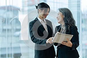 Two happy diverse coworker discussing report financial on tablet, working on project together