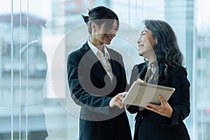 Two happy diverse coworker discussing report financial on tablet, working on project together