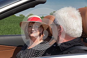 Two happy elderly people in a luxury convertible car on a sunny day