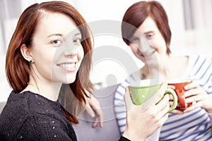 Two happy female friends with coffee cups