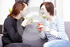 Two happy female friends with coffee cups