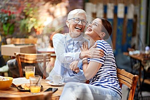 Two happy female friends of different generations having a wonderful time together while they have a drink in the bar. Leisure,