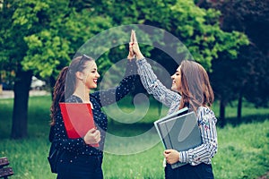 Two happy female students are giving high five after successfully learning