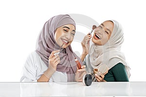 two happy friendly veiled girl vloggers holding brush and applying lipstick