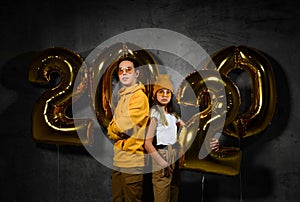 Two happy friends boy and a girl are celebrating a new year partywith ballonss numbers 2020 on a concrete background.