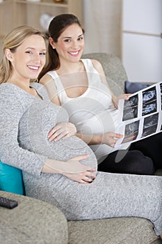 two happy friends checking baby scans