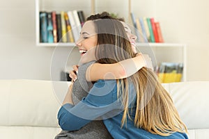 Two happy friends hugging at home