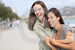 Two happy friends hugging and laughing outdoors