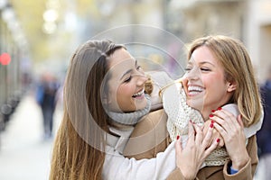 Two happy friends joking on the street in winter photo