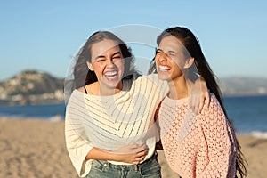 Two happy friends laughing hilariously at sunset photo