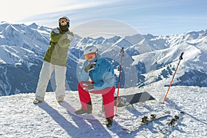 Two happy friends snowboarder and skier are having fun on ski slope with equipment in sunny day