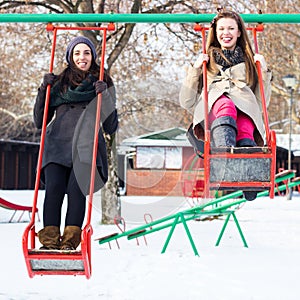 Two happy friends swinging