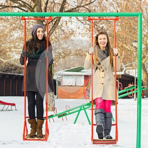 Two happy friends swinging on a swing