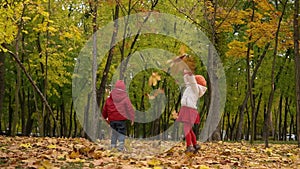 Two happy funny children kids boy Girl walking in park forest enjoying autumn fall nature weather. Kid Collect throw up