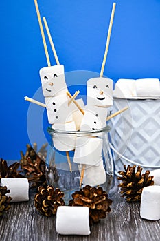 Two happy funny marshmallow snowmen. Marshmallow friends on blue background. Diy. Sweet treat for kids funny marshmallow snowman