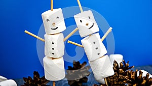 Two happy funny marshmallow snowmen. Marshmallow friends on blue background. Diy. Sweet treat for kids funny marshmallow snowman