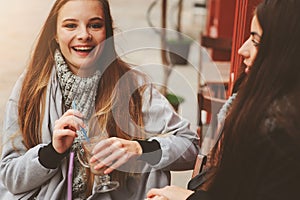 Two happy girl friends talking and drinking coffee in autumn city in cafe