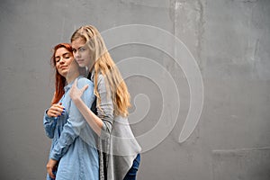 Two happy girlfriends are hugging on the background of a gray wall. Gentle hugs of a female lesbian couple. LGBT Same