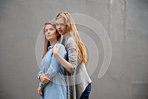 Two happy girlfriends are hugging on the background of a gray wall. Gentle hugs of a female lesbian couple. LGBT Same