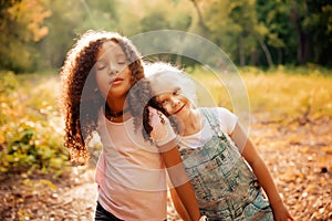 Two happy girls as friends hug each other in cheerful way. Little girlfriends in park.