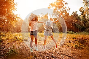 Two happy girls as friends hug each other in cheerful way. Little girlfriends in park.