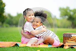 Two happy girls as friends hug each other in cheerful way. Little girlfriends in park. Childhood, family, love, friendship and