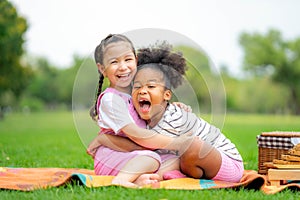 Two happy girls as friends hug each other in cheerful way. Little girlfriends in park. Childhood, family, love, friendship and