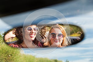 Two happy girls in a car rear-view mirror.