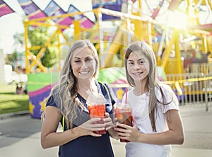 Two happy girls enjoying a cool drink at an amusement park