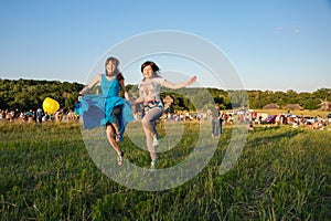 Two happy girls jumping high in blue sky on summer