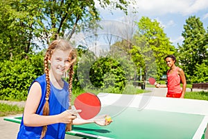 Two happy girls playing ping pong outside