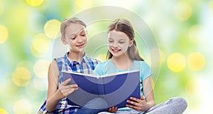 Two happy girls reading book over green background