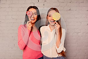 Two happy girls rejoicing with lollipop and smiling