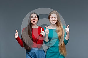 Two happy girls showing thumbs up