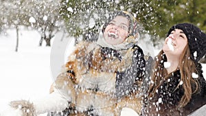 Two happy girls smiling and throwing up snow in the park. Slowly