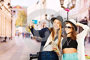 Two happy girls taking selfies with mobile phone