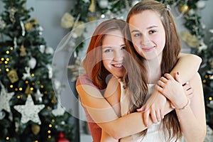 Two happy girls teenagers embrace near christmas photo