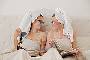 Two happy glamour woman friend wearing towel relaxing together