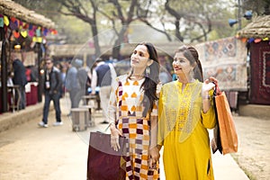 Two happy Indian women shopping at street market